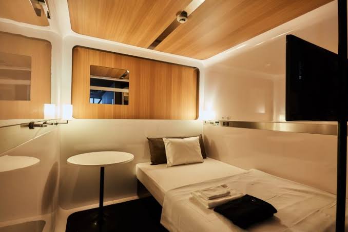 Compact sleeping cabin with a fitted bed, shelf and a panel at the opening