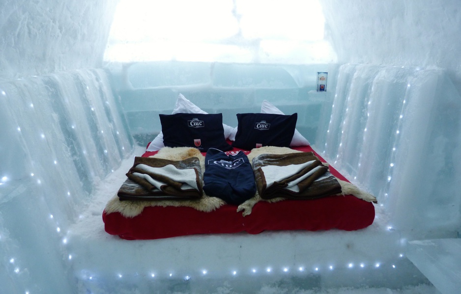 Ice chamber with carved walls and a low platform bed beside a glacial lake site